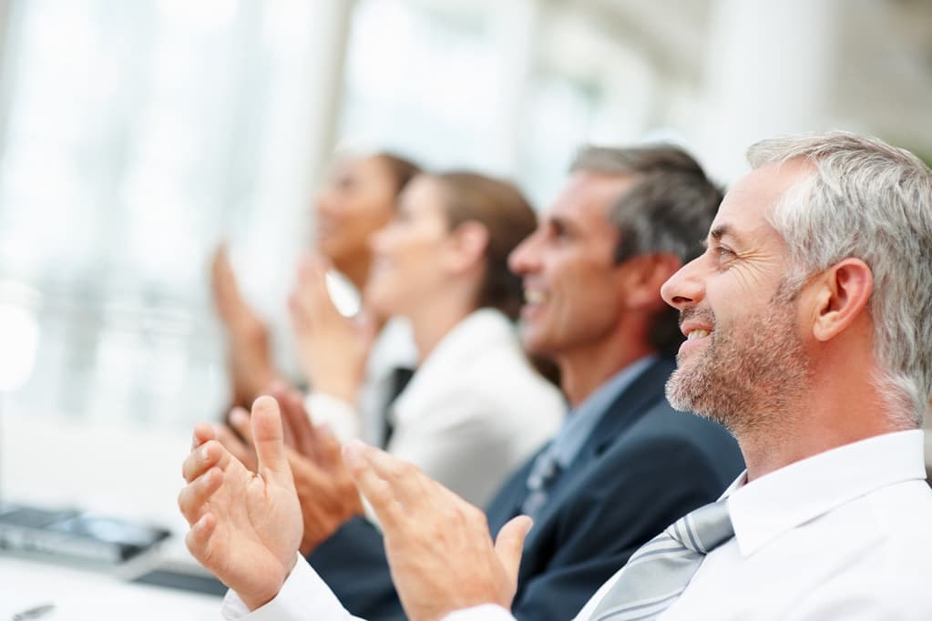 Equipo de profesionales aplaudiendo en una sala de juntas