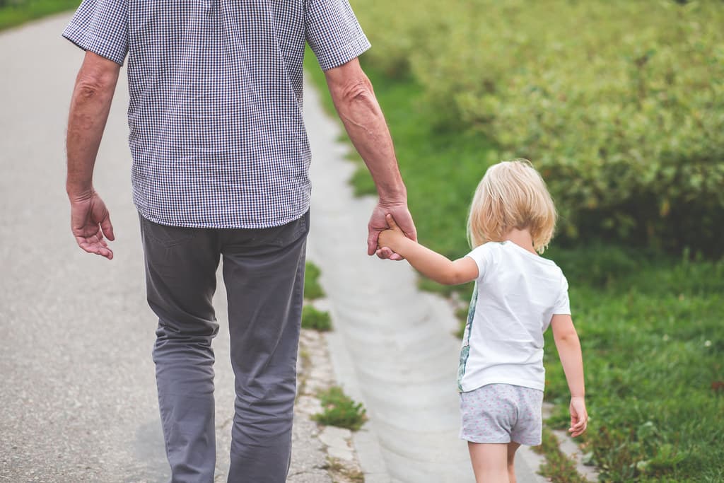Un abuelo camina de la mano con su nieta