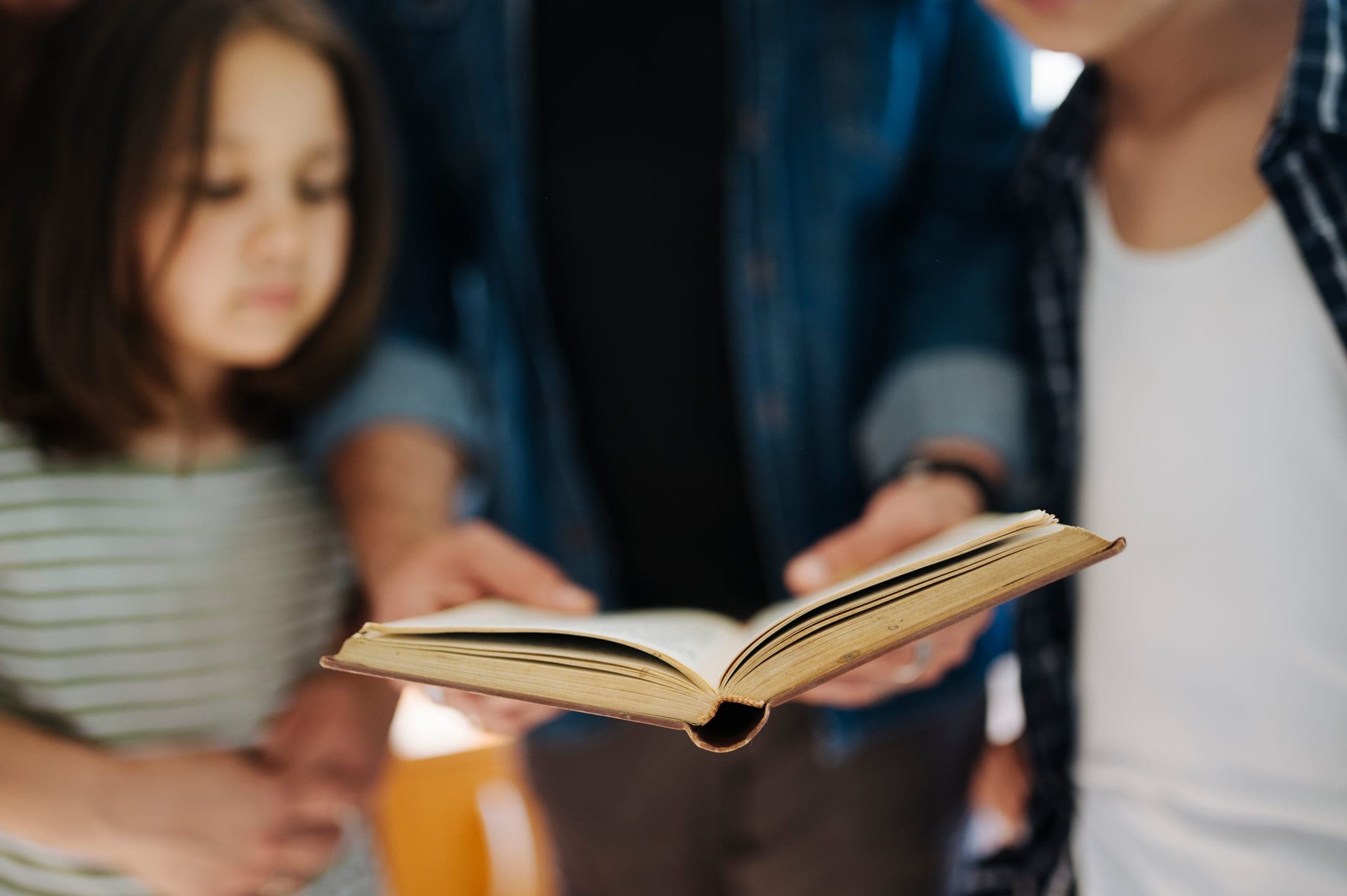 Un padre y sus hijos leen un libro juntos