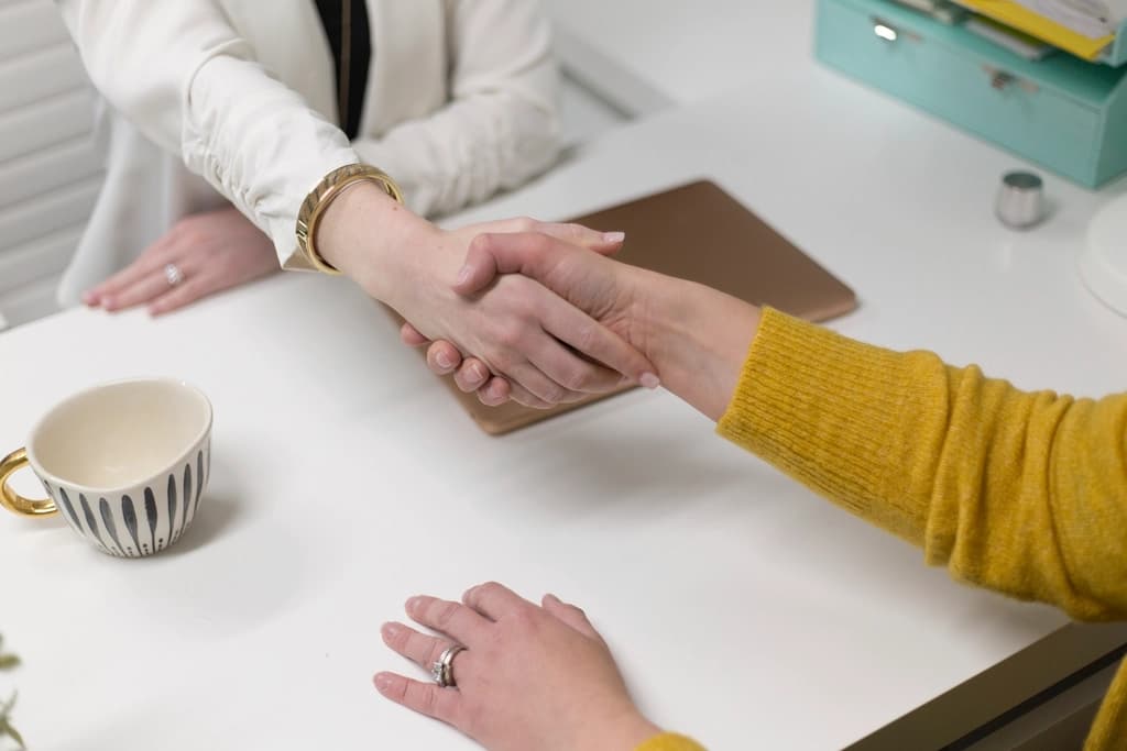 Dos personas dándose la mano sobre un escritorio
